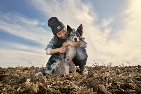 Female hugging her Australian Shepherd dog in a field.